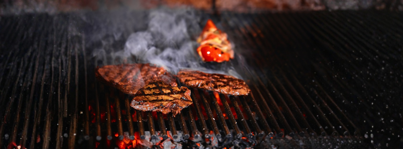 A charcoal smoker with meat on top