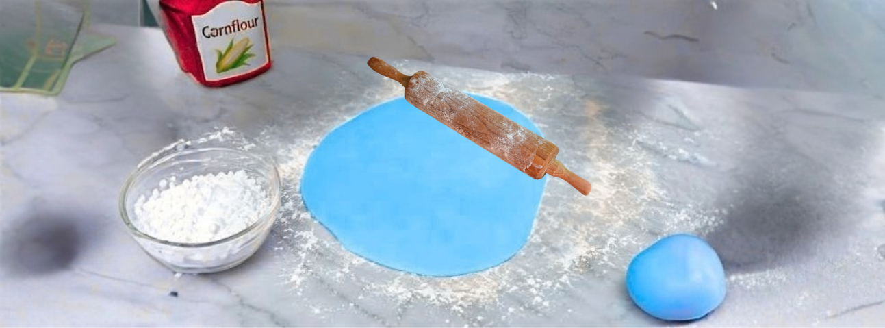 Fondant being kneaded on a smooth surface with powdered sugar nearby