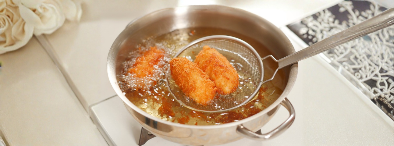 Golden-brown food frying in hot oil with bubbles rising around it