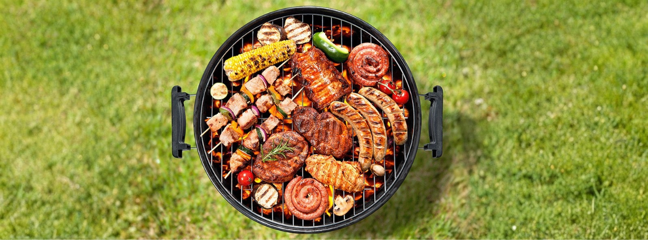 Meat grilling over charcoal with char marks forming and smoke rising