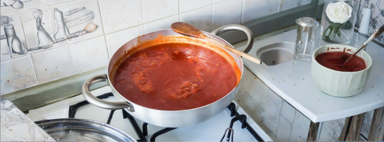 Tomato sauce simmering in a pot, deep red, with fresh herbs